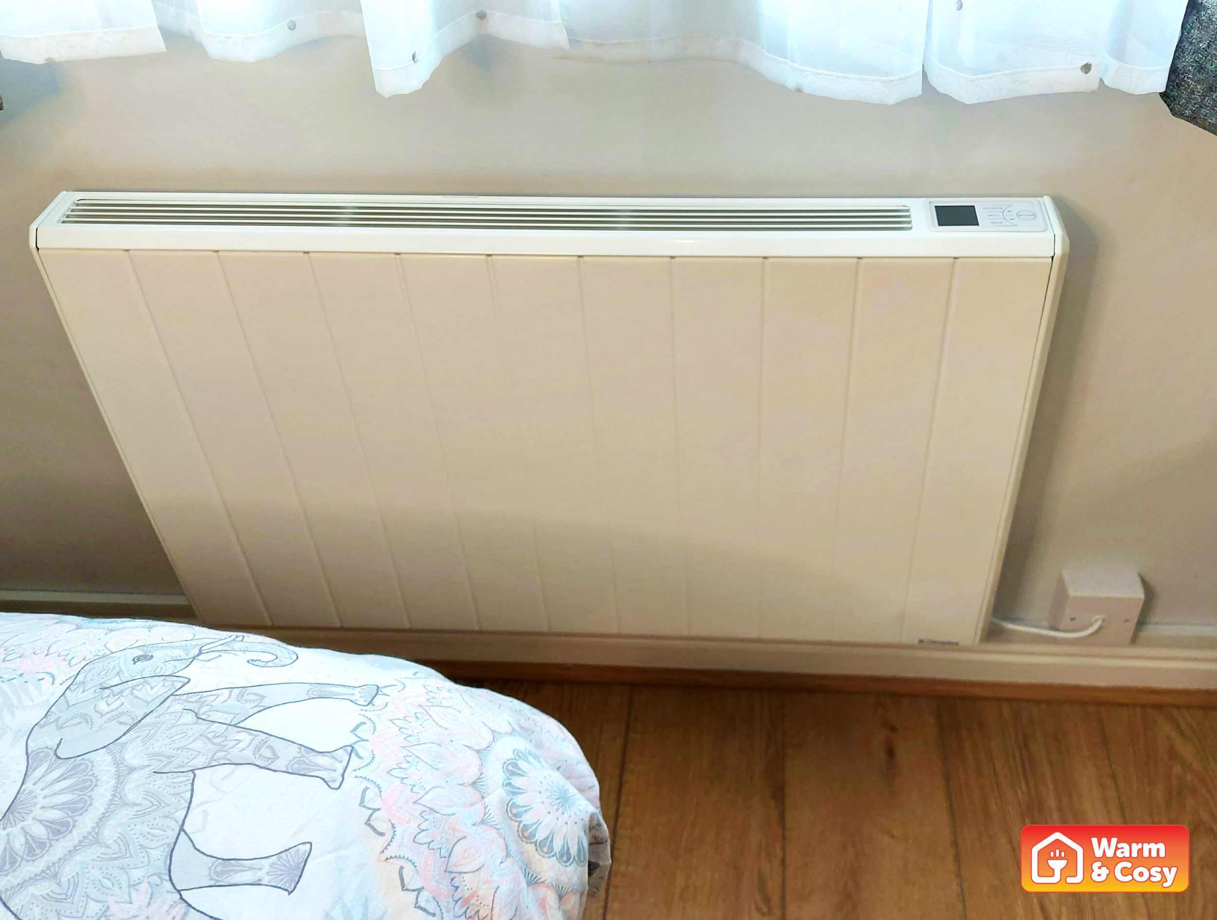 Slightly angled view from front and above of a Q-Rad electric radiator in a bedroom, highlighting its sleek design.