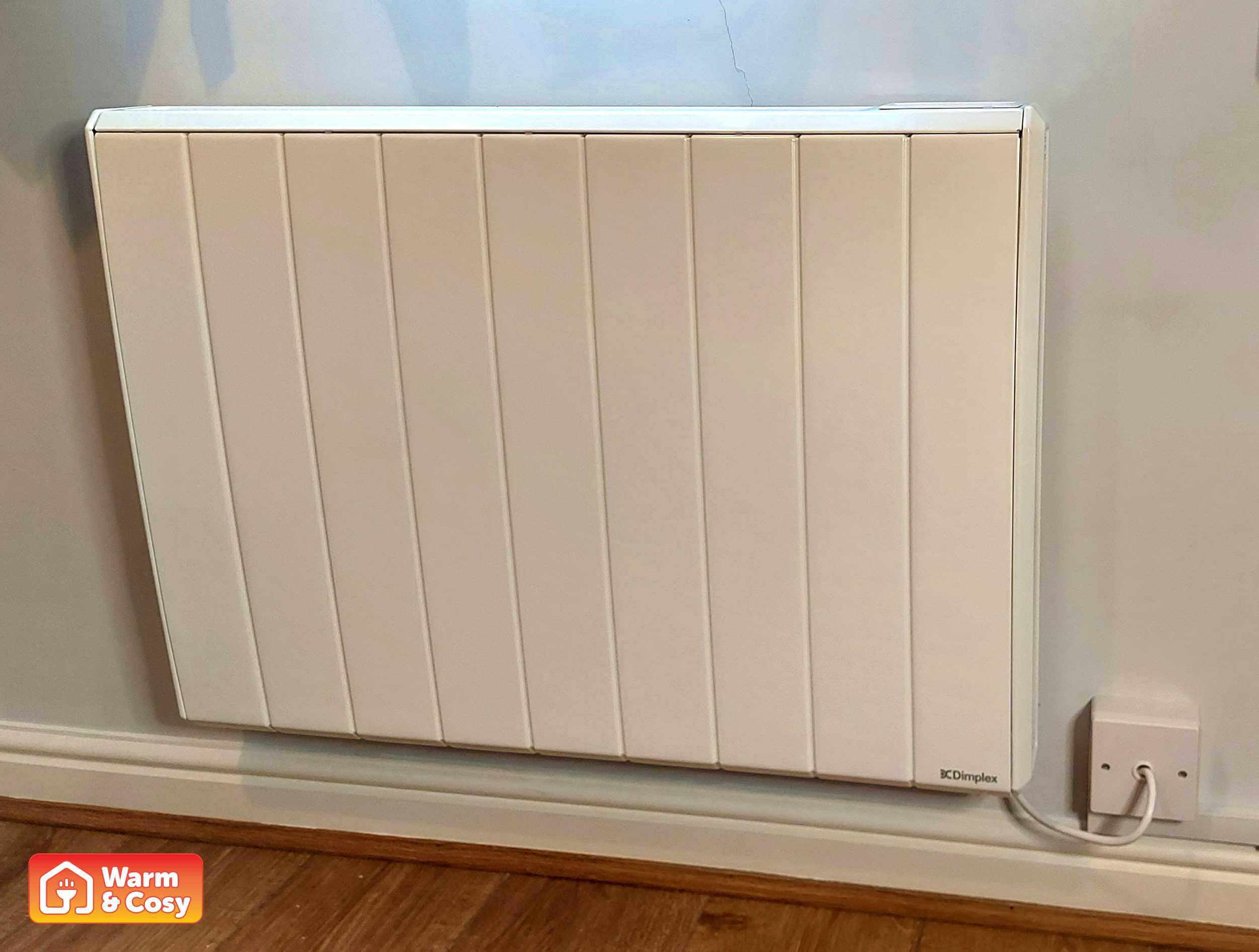 Front view of a Q-Rad electric radiator installed in a bedroom, blending seamlessly with the decor.